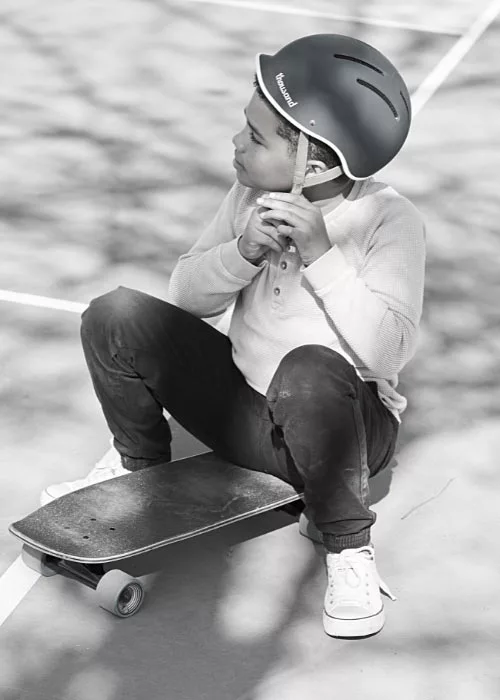 laessiger-Junge-mit-Helm-und-Skateboard